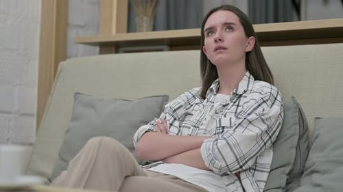 Relaxed Young Woman Sitting on Sofa and Thinking