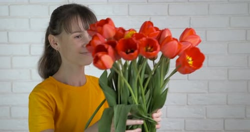 Child Holds and Smells Bouquet of Red Tulips