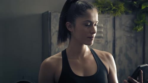 Young Woman Checks Phone in Fitness Studio