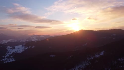 Aerial View of Winter Sunset Over Alpine Silhouette Mountains
