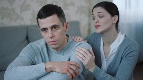 Woman Comforts Sad Man Sitting on a Couch