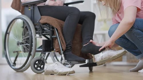 Caregiver Helping Person in Wheelchair with Shoes