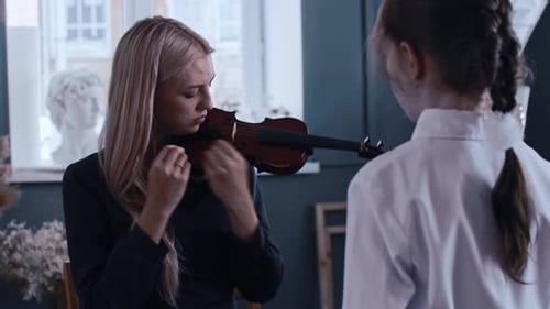 Woman Teaches Young Girl to Play the Violin