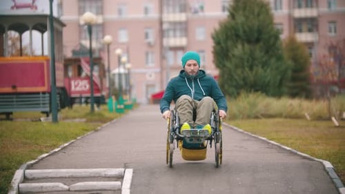 Man in Wheelchair Rides on Paved Path