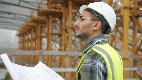 Portrait of Engineer Planning Work at Construction Site Looking at Blueprint Outdoors