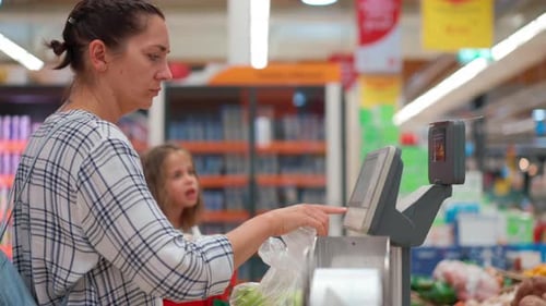 Woman Weighs Vegetables Bought in Supermarket on the Scales of a Selfservice Store