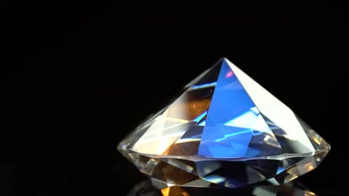 Diamant schimmert mit blauen und orangefarbenen Reflexen. Schwarzer Hintergrund