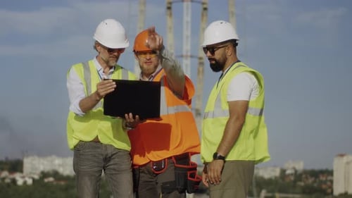 Builders Using Laptop on Construction Site