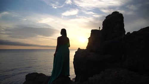 Side View a Young Beautiful Sensual Woman in a Mint Long Dress Posing on a Volcanic Rock High Above