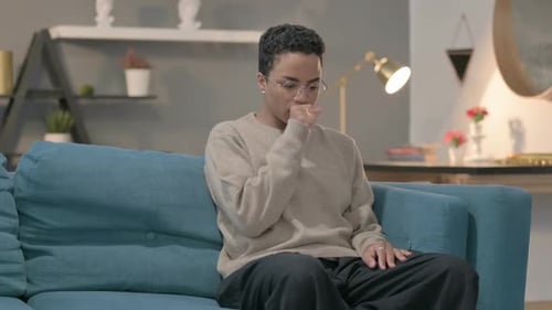 Woman Coughs While Sitting on Blue Couch