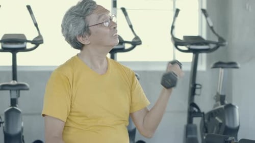 Homme âgé assis soulevant des haltères pour entraîner les bras et renforcer les muscles.