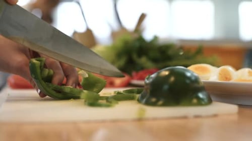 Green Bell Pepper Being Sliced on Cutting Board
