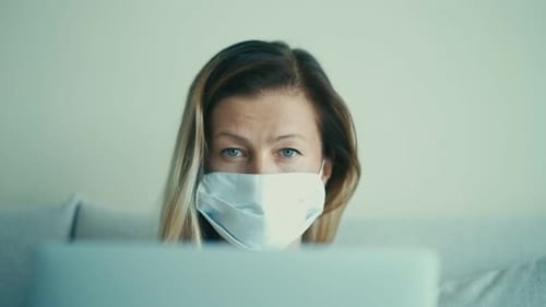 Woman Looking at Laptop with Mask Around Neck