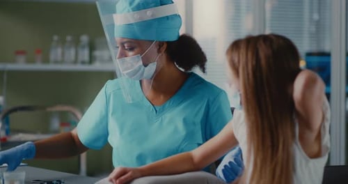 Ethnic Medical Practitioner Vaccinating Girl in Clinic