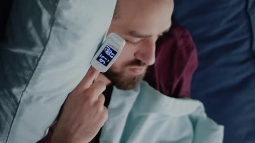 Vídeo vertical de primer plano de hombre enfermo durmiendo en el sofá con oxímetro en el dedo