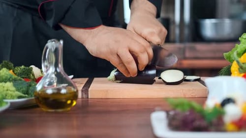 Male Chef Hand Cutting Raw Eggplant Using Knife