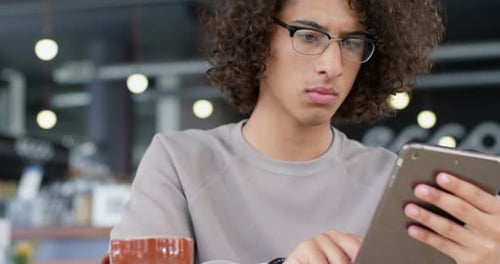 Young Adult Using Tablet in Modern Cafe