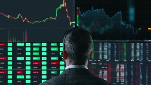Trader is Working with Multiple Computer Screens Full of Charts and Data Analysis and Stock Broker