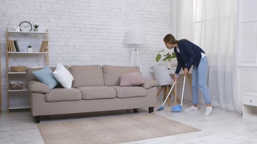 Woman Sweeping Floor in Bright, Modern Living Room