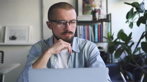 Front View of Young Bearded Businessman Working with Laptop at Table in Home. Spbd