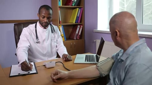 Doctor Taking Patient's Blood Pressure in Office