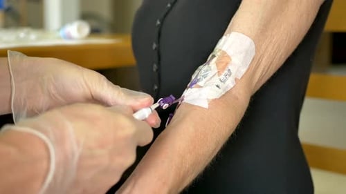 Medical nurse doing an at home iv patient visit wearing sterile gloves and cleaning a picc line with