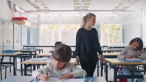 Female School Teacher Walking Between Pupils