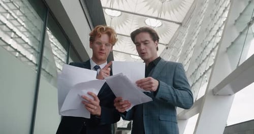 Dois empresários estão discutindo um plano de negócios para o crescimento das vendas, procurando em jornais em pé