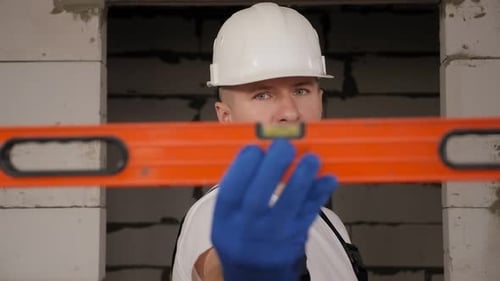Construction Worker Checks Level Inside Building