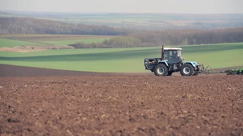 Un tractor arando y sembrando en el campo