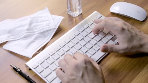 Hands Typing on Keyboard with Masks and Sanitizer