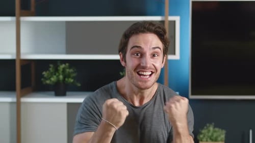 Excited young man celebrates good news at home