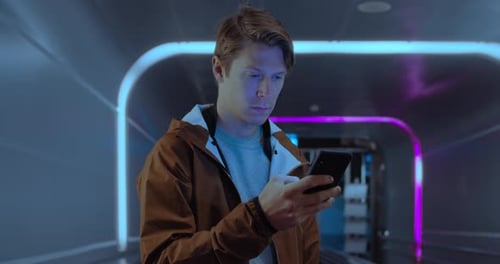 Young Adult Using Smartphone in Illuminated Tunnel