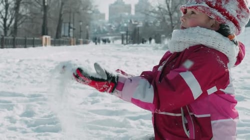 Teenager-Mädchen wirft Schnee im Winterpark. Mädchen spielt im Winter mit Schnee