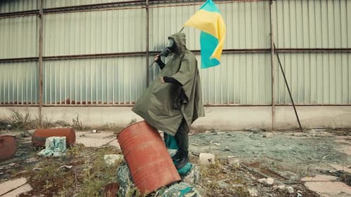 Soldier Man with Gas Mask Waves Ukrainian Flag in a War Warehouse