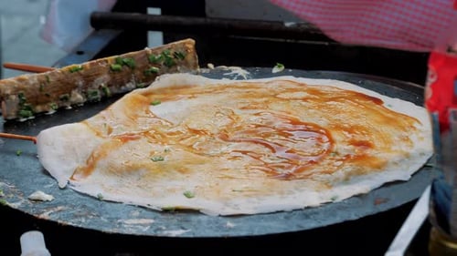 Traditional Jian Bing Being Grilled and Wrapped on Street Food. Fast Food and Cooking Concept