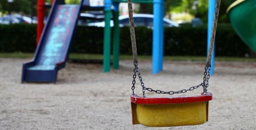 Empty Swing Gently Swaying in City Playground