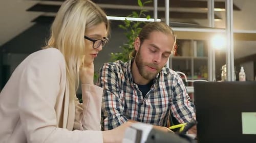 Homme barbu qui parle avec une blonde assez satisfaite dans des lunettes pendant un travail conjoint