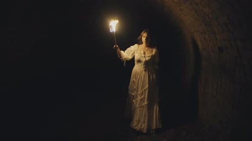 Woman in White Dress Holding Torch in Dark Tunnel