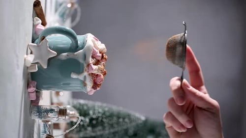 Hand dusting cocoa powder over holiday mug