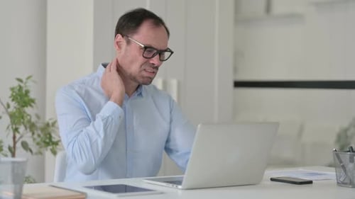 Man Works On Laptop, Rubs Neck