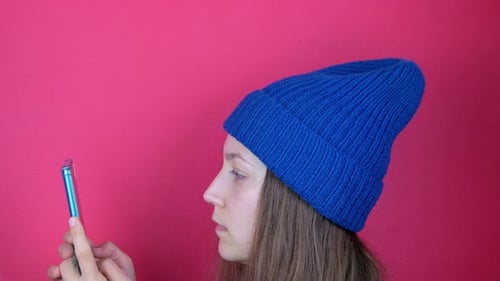 Young Adult Using Smartphone in Front of Pink Background