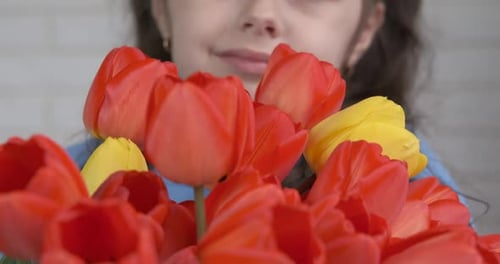 Smiling Girl Holding Bouquet of Red and Yellow Tulips