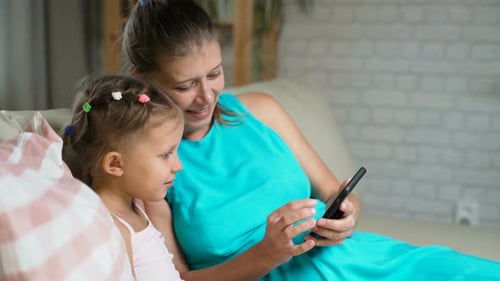 Woman and Child Looking at Phone Together