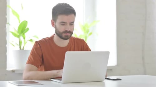Young Man Working on Laptop in Office