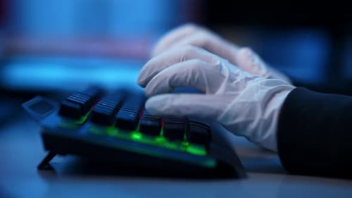 Nahaufnahme Seitenansicht von Händen in weißen Handschuhen, die auf einer Tastatur mit Hintergrundbeleuchtung tippen