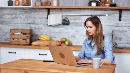 Woman Working on Laptop in Kitchen