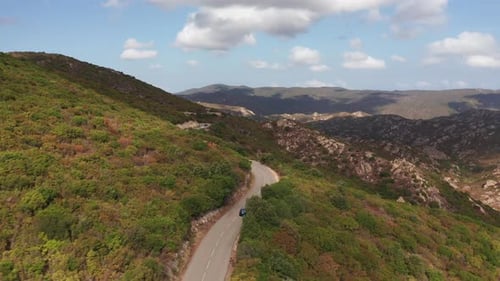 Aerial Shot of Electric Car Driving on the Sunny Road Highway to Mountains Landscape