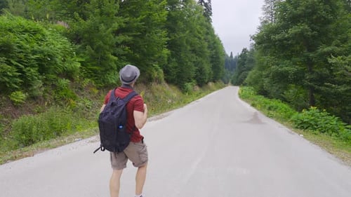 Einsamer Mann, der auf der Straße im Wald läuft.