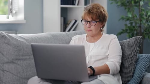 Woman Typing on Laptop Computer While Seated on Couch